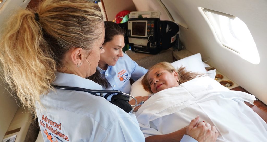Flight nurses comfort a patient laying in the air ambulance jet.